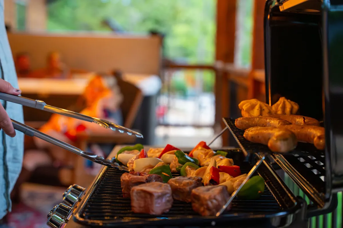 A lively outdoor grilling scene with someone tending to a BBQ, meats and vegetables sizzling on the grill, and a cozy background seating area set for alfresco dining.